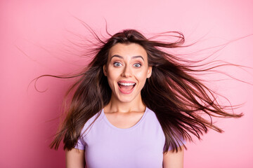 Portrait of amazed young lady open mouth flowing hair dressed casual isolated on pink color...