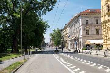 Fototapeta na wymiar The slow holiday traffic on the road and the empty street in the historical center of Szeged, Hungary known for its beautiful old traditional architecture