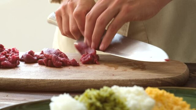Crop woman cutting meat in kitchen