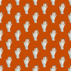 Seamless pattern. Top view of a white hand with black nails on an orange background. Concept abstraction, Halloween, art.