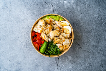 Healthy Protein Fitness Food Chicken, Egg, Spinach, Avocado and Cucumber with Fitness Equipment Dumbbells for Athlete in Plastic Bowl.