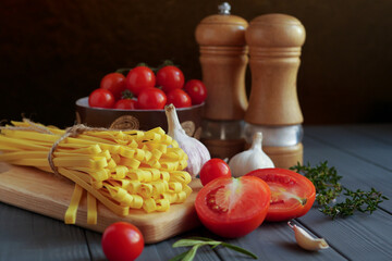 Tagliatelle pasta with tomatoes and spices on a gray wooden background