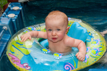 Being watched by both mom and grandma a baby child is playing in hot tub with a floating boat...