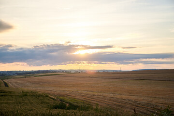 Beautiful field covered with stubble and blue yellow orange pink sky over it. Agricultural development in countryside. Ecological conservation concept. Amazing natural view at sunset.