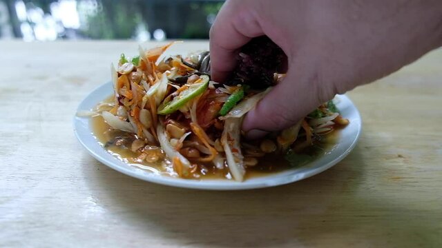 Somtum Thai spicy green papaya salad eat with black sticky rice by hand, eating in Thai style