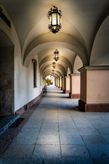 Arcades or archway with long corridor illuminated by vintage lanterns. Townhall building on city...