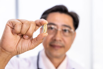 Senior Asian doctor researcher holding and looking at pill