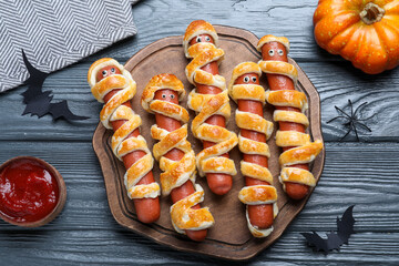 Cute sausage mummies served on wooden table, flat lay. Halloween party food