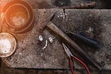 Silver jewelry making equipment placed on a wooden stand.