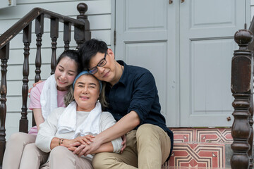 Asian young woman and man hug and take care senior parent grandmom with happy smile on outdoor terrce house.