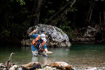 A fly fisherman fishing a trouts in mountain river