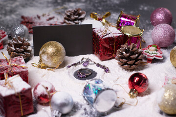 Fototapeta na wymiar purple jewelry - ring and earrings - next to New Year's decorations in the snow. Christmas trees, balls, snowflakes, gifts, cones. Christmas mood. Flatly photo.