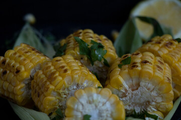 Grilled corn on green leaves with lemon. Yummy.