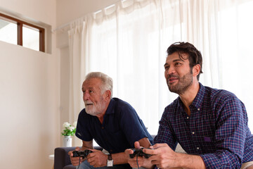 Happy senior father and adult son playing video game together at home. Elderly father and adult son spending time together. people, family, holiday concept