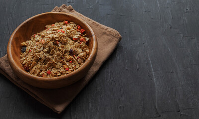 On a black background in a wooden bowl a healthy breakfast of berries, raisins and sprouted grains of wheat