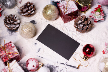 black business card next to New Year's decorations in the snow. Christmas trees, balls, snowflakes, gifts, cones. Christmas mood. Flatly photo. 