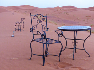 Chairs and table in the middle of the dunes of the Erg Chebbi desert, Merzouga, Sahara, Morocco.