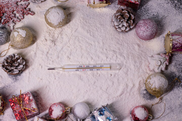 Fototapeta na wymiar medical thermometer next to New Year's decorations in the snow. Christmas trees, balls, snowflakes, gifts, cones. Christmas mood. Flatly photo. 