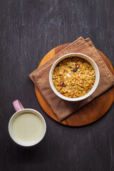 In a ceramic small plate there are berry muesli, and next to a mug of cow's milk