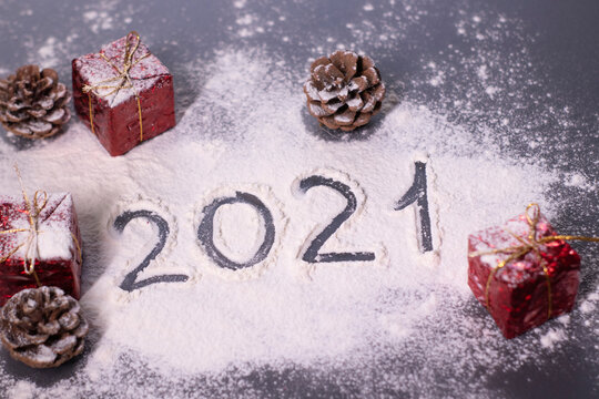 Christmas decorations, decor elements in the snow. red gifts and cones. Finger-drawn '2021' in the snow. Christmas mood. Flatly photo.