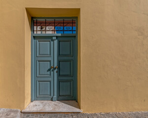 Fototapeta premium painted wooden external door and colorful wall by the sidewalk, Athens Greece. Space for text
