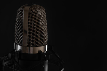 Studio condenser microphone for recording voices, isolated on black background. Copy space on right. Music concept.