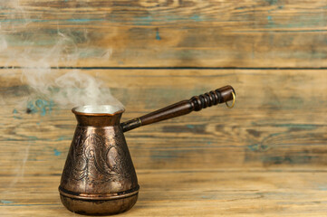 coffee pot with hot steam from freshly brewed coffee on wooden background