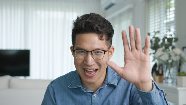 Portrait or headshot of young adult asian handsome man or model wearing eye glasses with cool hair big smiling confident and looking to camera with feeling happy and positive in living room at home.