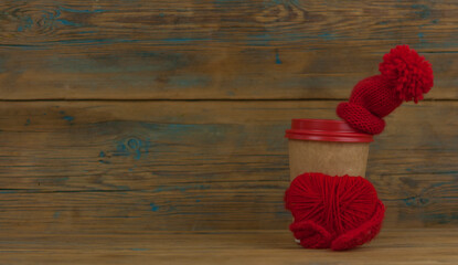 disposable cup for beverages coffee or tea in cardboard holder, knit toy red hat and scarf, winter