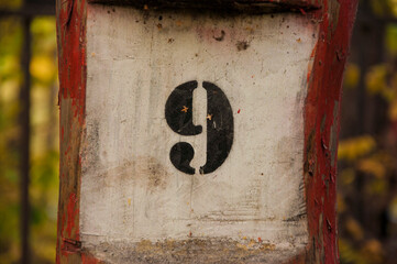 the number nine painted to a post, aged worn look