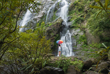 Woman standing on a rock with a waterfall in front