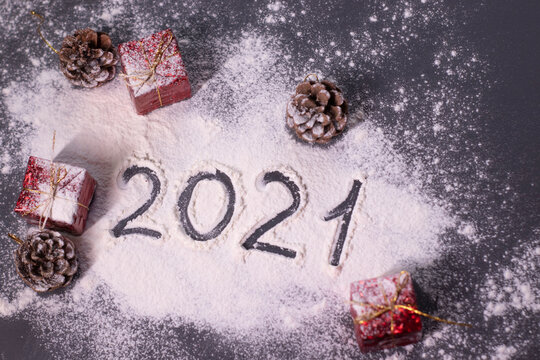 Christmas decorations, decor elements in the snow. red gifts and cones. Finger-drawn '2021' in the snow. Christmas mood. Flatly photo.