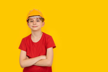 Teenager in protective helmet on yellow background. Guy dreams of future career in construction.