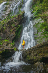 Woman standing on a rock with a waterfall in front