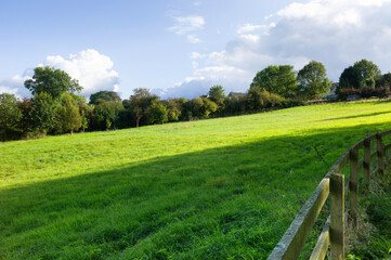 Fresh green landscape on a hill with fence in foreground in the Cotswold, United Kingdom