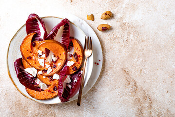 Roasted pumpkin salad with radicchio leaves, feta cheese, nuts and cranberries. Thanksgiving side dish dinner recipe. Healthy seasonal fall or autumn food