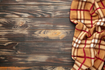 Checkered plaid on brown wooden background with copy space