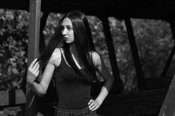 Long-haired young woman in wooden gazebo in black and white