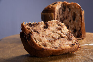 Panettone with chocolate chips on rustic wood with gray background, selective focus.