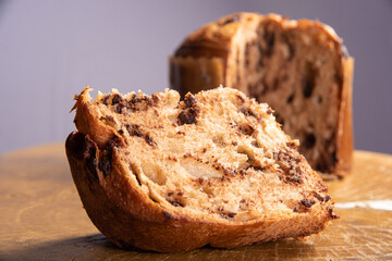 Panettone with chocolate chips on rustic wood with gray background, selective focus.