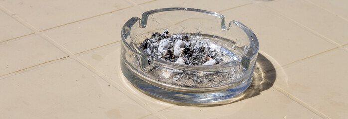 Ash tray and cigarette butts and cigarette ash on the table