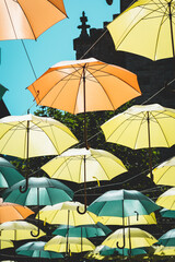 Fototapeta na wymiar Colorful umbrellas hung across the street creating a pattern