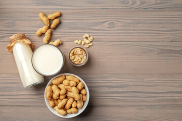 Vegan peanut milk in glass bottle with peanuts on wooden board