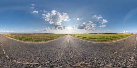 Full spherical seamless panorama 360 degrees angle view on no traffic old asphalt road among fields with clear sky and white clouds in equirectangular projection, VR AR content