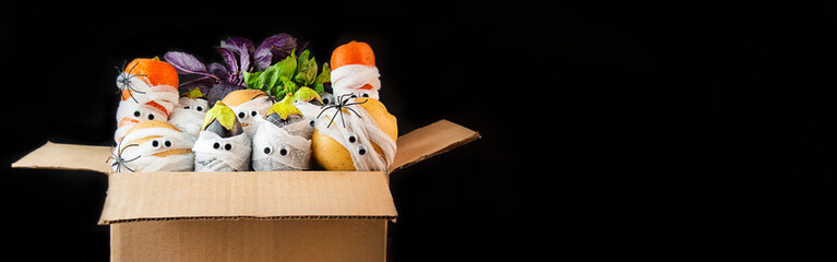 Halloween background. Creepy vegetables with eyes in medical bandages in a shopping box on a dark background. Halloween food. Baner. Copy space.