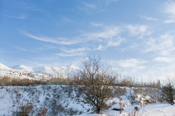 Snowy beautiful winter landscape of the Tien Shan mountains in Uzbekistan on a frosty Sunny day with blue sky and Cirrus clouds. Chimgan