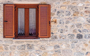 Fototapeta na wymiar natural wood window frame with shutters on stonewall, space for text