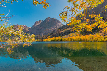 Fototapeta na wymiar Silver Lake and a fisherman and boat are surrounded by fall color in California