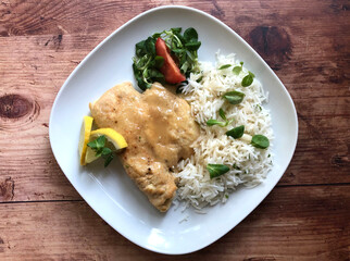 Italian classic dish scaloppine. In pan seared roasted chicken meat with rice and salad bouquet.