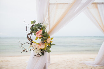 Wedding bamboo gazebo, decorated with tropical flowers and coloured fabrics on the paradise beach...